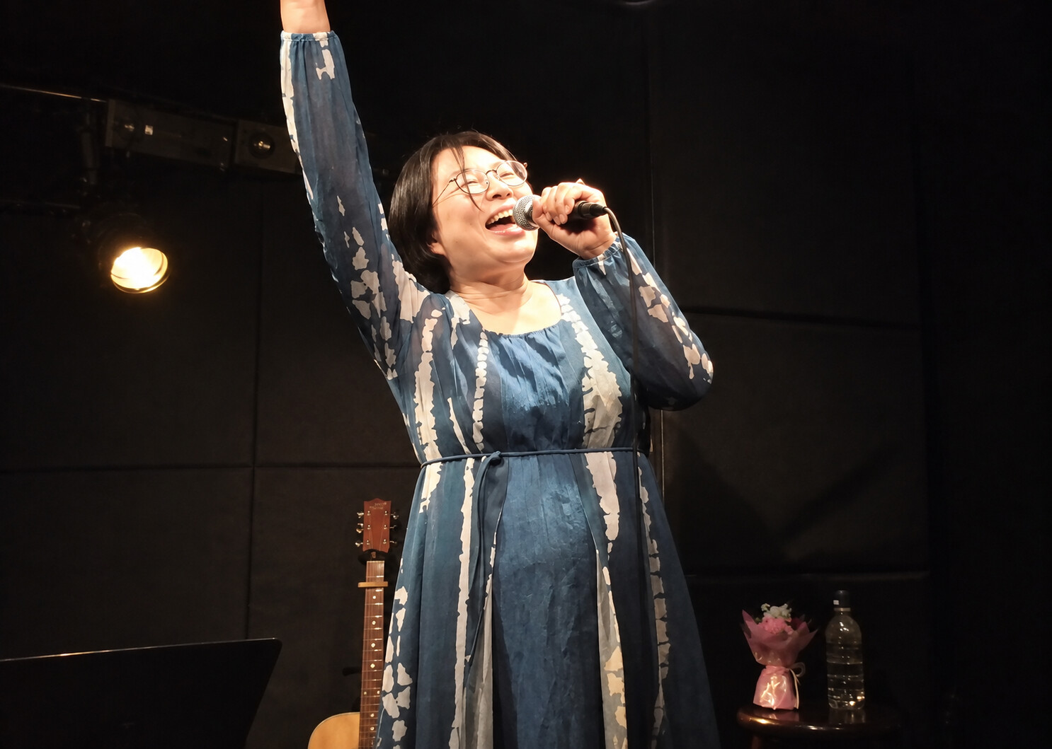 片腕を高く掲げて歌うPLUM