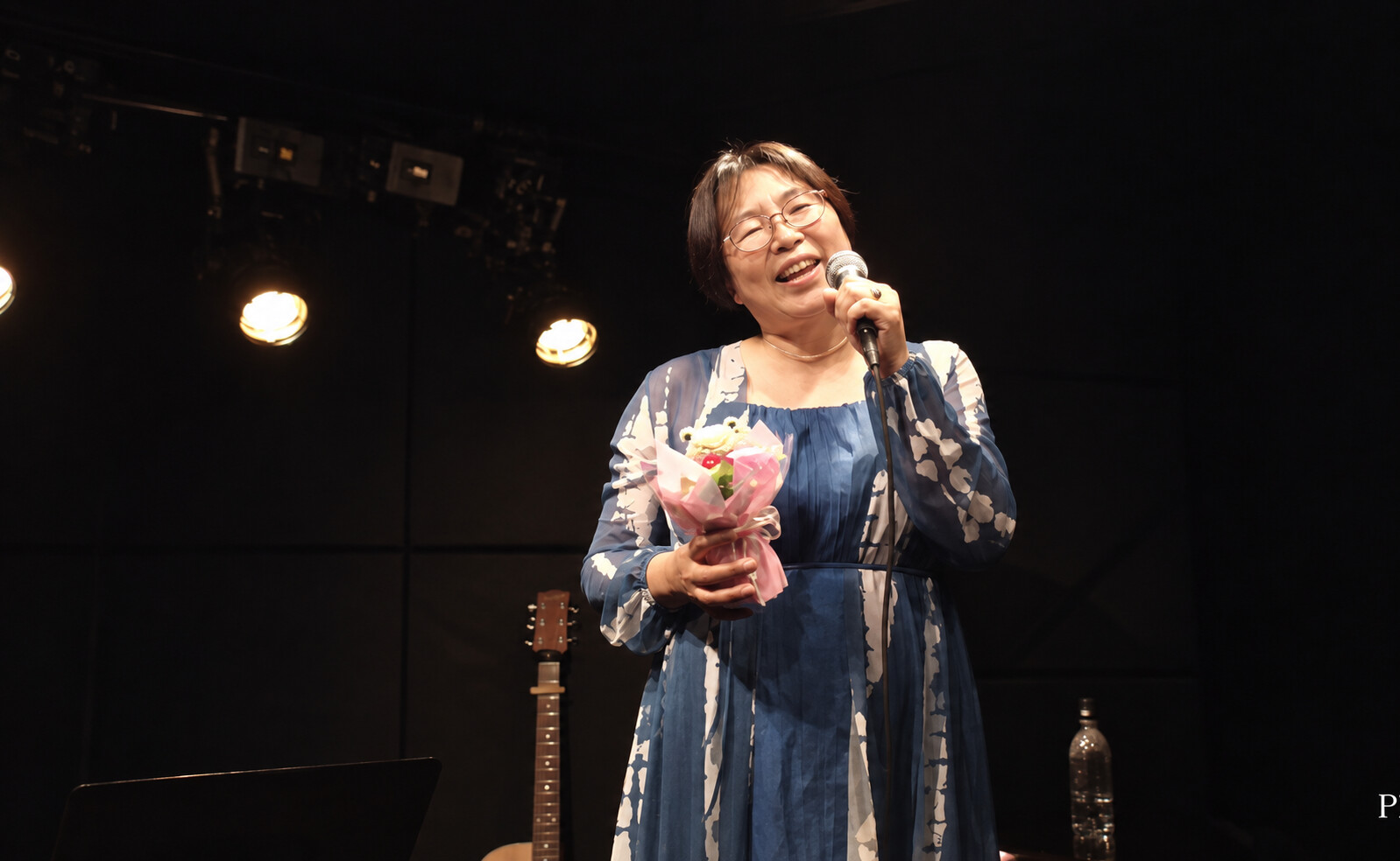 受け取った花束を手に、笑顔で歌うPLUM